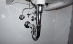 Abwasserleitung mit Siphon unter einem Waschbecken – undichte Rohrverbindungen können Kanalgeruch und Abwassergeruch im Badezimmer verursachen.